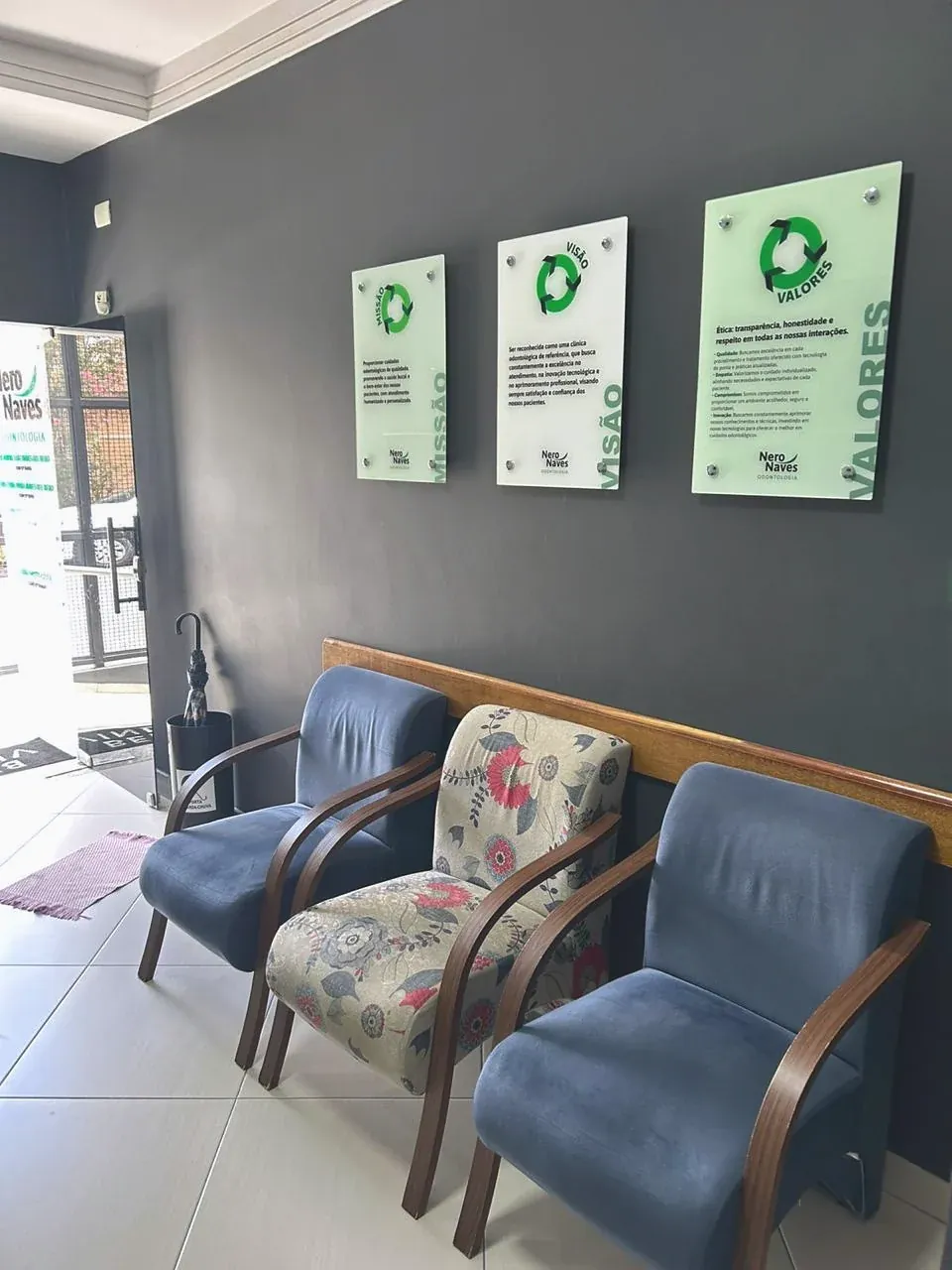 A sala de espera, com duas poltronas azuis e uma estampada de flores.
